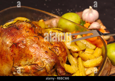 oven baked apple chicken in a glass dish on a wooden plank Stock Photo