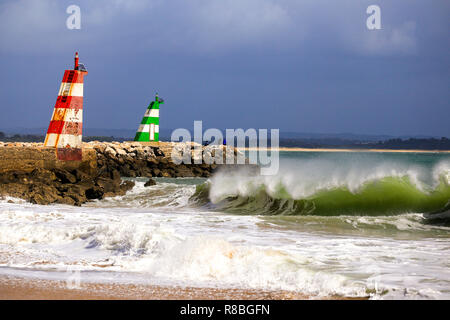 Waves breaking on the beach infront of the lred & green ighthouses in Lagos, Portugal. Stock Photo