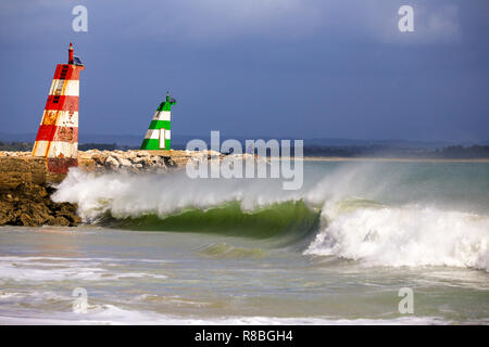 Waves breaking on the beach infront of the lred & green ighthouses in Lagos, Portugal. Stock Photo