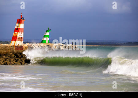 Waves breaking on the beach infront of the lred & green ighthouses in Lagos, Portugal. Stock Photo