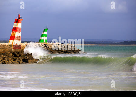 Waves breaking on the beach infront of the lred & green ighthouses in Lagos, Portugal. Stock Photo