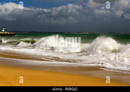 Waves breaking on the beach infront of the lred & green ighthouses in Lagos, Portugal. Stock Photo