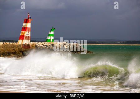 Waves breaking on the beach infront of the lred & green ighthouses in Lagos, Portugal. Stock Photo