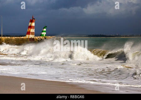 Waves breaking on the beach infront of the lred & green ighthouses in Lagos, Portugal. Stock Photo