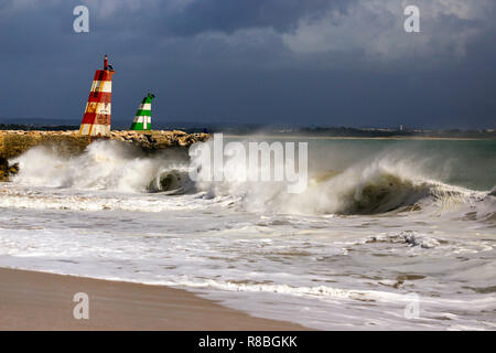 Waves breaking on the beach infront of the lred & green ighthouses in Lagos, Portugal. Stock Photo