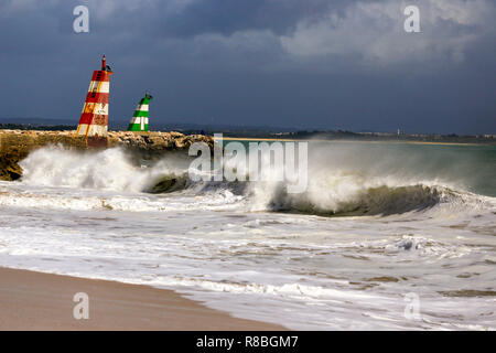 Waves breaking on the beach infront of the lred & green ighthouses in Lagos, Portugal. Stock Photo