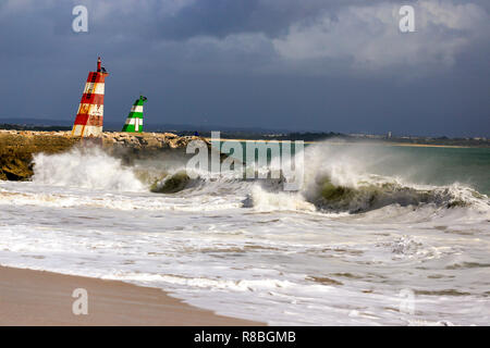 Waves breaking on the beach infront of the lred & green ighthouses in Lagos, Portugal. Stock Photo