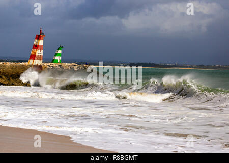 Waves breaking on the beach infront of the lred & green ighthouses in Lagos, Portugal. Stock Photo