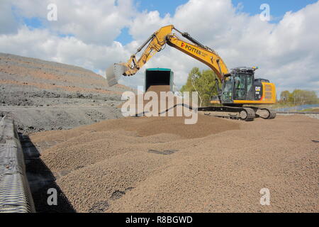 A Caterpillar 320E levelling out lightweight expanded clay aggregate , which is used for backfilling behind a railway bridge on the FARRRS link road. Stock Photo