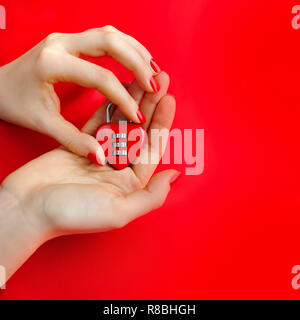 Padlock heart-shape in women's hands on red background Stock Photo