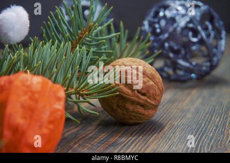 Christmas background with festive red Santa hat and colorful yellow candle with pine foliage and fresh whole nuts in their shells Stock Photo