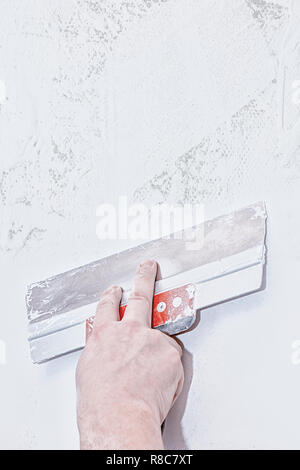 Hand with trowel, repair wall, Trowel with putty structure, the process of applying a layer of trowel, work with putty. Copy space Stock Photo