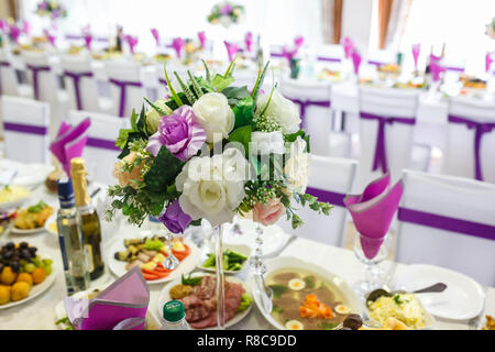 Beautiful flowers on elegant dinner table in wedding day. Decorations served on the festive table in violet background Stock Photo