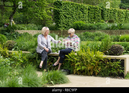 Two senior ladies, enjoying an informal afternoon tea, surrounded by greenery at the Old Rectory open under the National Garden Scheme; Quinton, UK Stock Photo