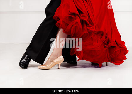 Close up of dancers feet. Ballroom dancers on the dance floor. A man in trousers, a woman in a magnificent ballroom red dress. Stock Photo