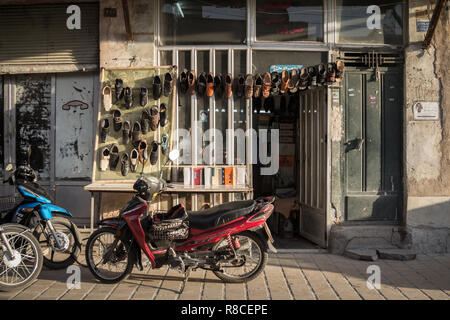 ISFAHAN, IRAN - AUGUST 20, 2018: Motorcycles standing in front og a shoemaker shop, with shoes hand in front. The Isfahan bazar is one of the symbols  Stock Photo