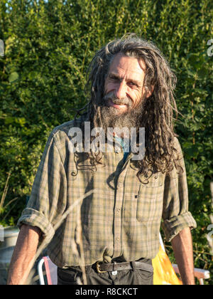 An outdoors portrait of Peter the traveller with long untidy hair and beard and a ready smile. Stock Photo