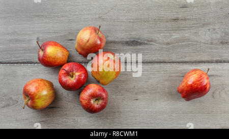Tabletop view, 7 red glossy apples on gray wooden desk. Stock Photo