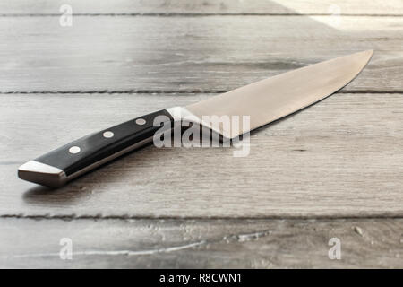 Chef's knife on wooden boards desk. Stock Photo