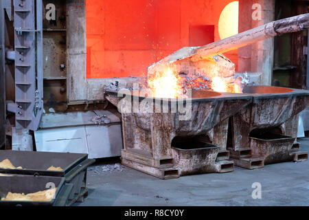 skimming melted aluminum for removing the dross before casting. Aluminum foundry works showing an open furnace Stock Photo