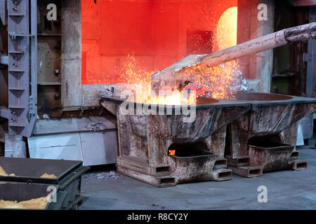 skimming melted aluminum for removing the dross before casting. Aluminum foundry works showing an open furnace Stock Photo