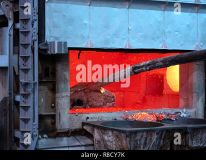 skimming melted aluminum for removing the dross before casting. Aluminum foundry works showing an open furnace Stock Photo