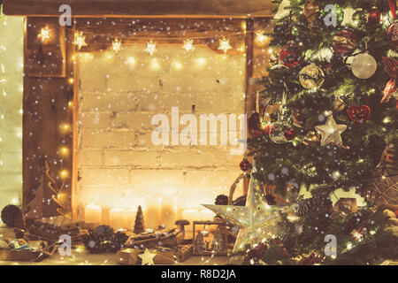 Christmas setting, decorated fireplace, wooden mantelpiece fire surround, lit up Christmas tree with baubles ornaments, stars, candles, toned, vintage effect, created snow, selective focus Stock Photo