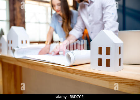 Young woman and man as an architects working with blueprints and house models in the office, close-up view Stock Photo