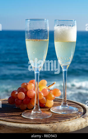 Champagne, prosecco or cava served with pink grape in two glasses on outside terrace with sea view close up Stock Photo