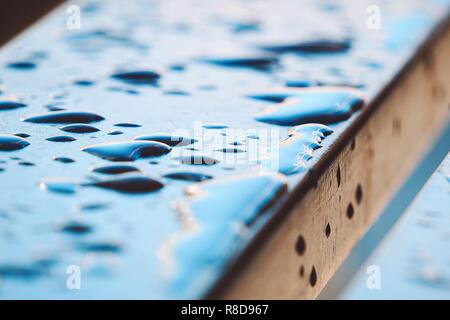 the raindrops on the wooden bench in the street in the park Stock Photo