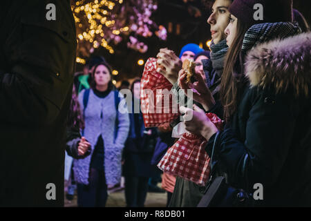 Vienna, Austria - November 24, 2018: Young people eating donuts at Christmas World on Rathausplatz, traditional Christmas Market in Vienna with over 1 Stock Photo