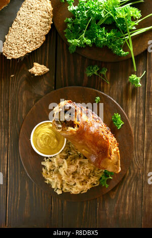 Pork knuckle with braised cabbage (sauerkraut) and mustard on wooden table. Top view Stock Photo