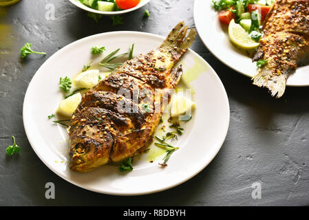 Fried fish on plate over black stone table. Stock Photo