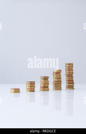 Stacks of Euro coins in ascending order on light gray table and background. Simple design, selective focus, Concept photo of financial growth. Stock Photo
