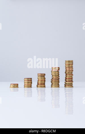 Stacks of Euro coins in ascending order on light gray table and background. Simple and minimalistic design. Concept photo of financial growth. Stock Photo
