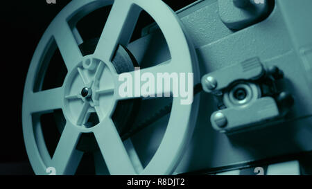 Film projector with dramatic blue lighting and selective focus. Retro film production still life. Concept of film-making. Old 8mm projector is turning Stock Photo