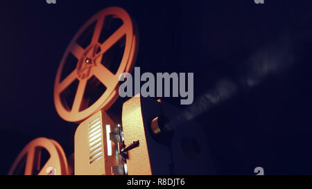 Vintage objects, cinematograph concept. Retro film projector playing in the dark room. Old-fashioned antique super 8mm film projector projecting beam  Stock Photo