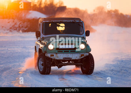 Russian UAZ 469 moving on ice of a frosn river at sunset Stock Photo