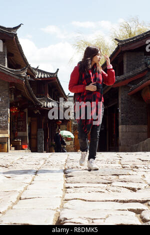 Sight see : chinese travel pretty girl walk on the rock road of historic old town in Lijiang,  Yunnan province with old building background Stock Photo