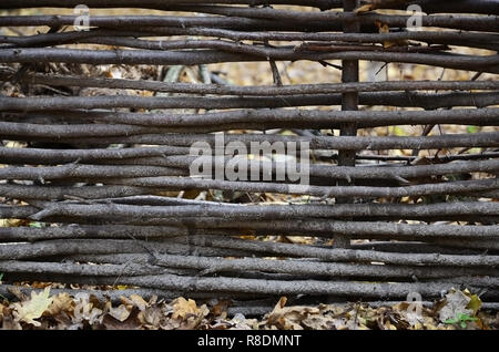 Decorative fence from wooden branches. Rare wooden wall Handmade small wooden thin branches in Ukrainian western style Stock Photo