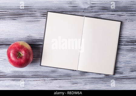 Open blank sketchbook and red apple over white wooden background Stock Photo