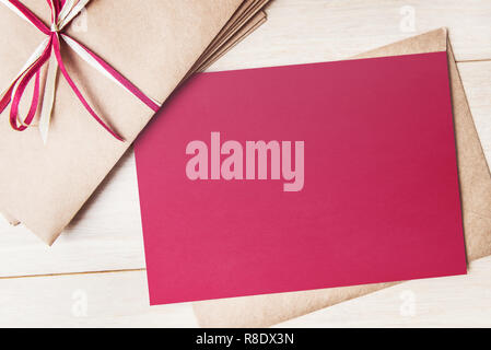 Mock up of red card with envelopes pile on wooden table Stock Photo