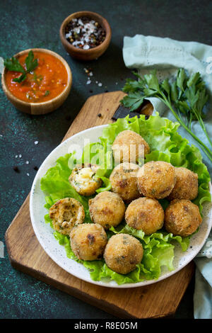 Arancini - traditional Italian Rice Balls with Mozzarella and Sun-dried tomatoes, served with tomato sauce. Stock Photo