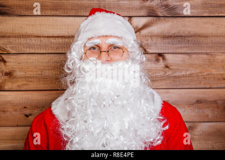 Close-up portrait of man in Santa Claus costume on wooden background. Christmas concept Stock Photo