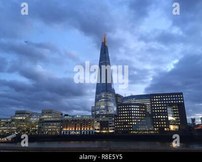 London, England, February 12 2018. The famous skyscraper at dusk across the river Thames illuminated by interior lights with cloudy sky background. Stock Photo