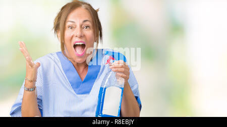 Middle age brunette cleaner woman wearing housework uniform over isolated background very happy and excited, winner expression celebrating victory scr Stock Photo