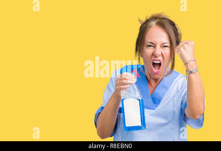 Middle age brunette cleaner woman wearing housework uniform over isolated background annoyed and frustrated shouting with anger, crazy and yelling wit Stock Photo