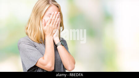 Beautiful young woman wearing oversize casual t-shirt over isolated background with sad expression covering face with hands while crying. Depression c Stock Photo