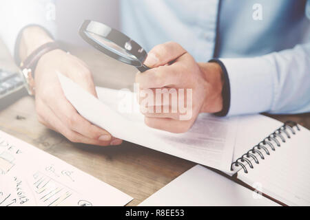 Businessman looking through a magnifying glass to documents Stock Photo