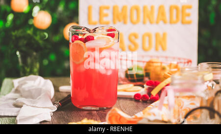 Raspberry lemonade garnished with fresh lemon and raspberries in drinking mason jars. Stock Photo